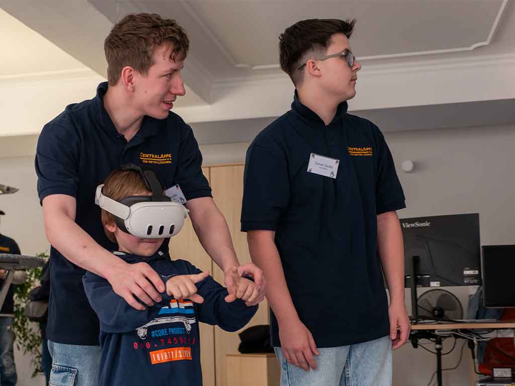 Zwei Mitarbeiter helfen einem Besucher beim Testen einer VR-Brille.